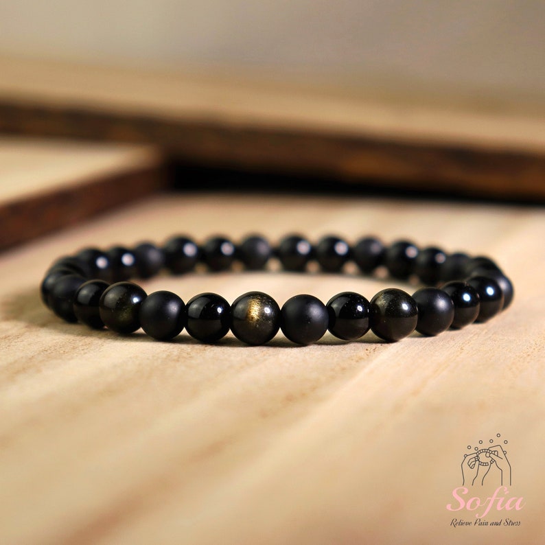 Peut inclure: Bracelet en perles noires avec des reflets dor&eacute;s. Le bracelet est compos&eacute; de perles noires mates et de perles de pyrite dor&eacute;e.
