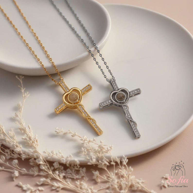 Puede incluir: Dos collares de cruz, uno dorado y otro plateado, cada uno con un centro en forma de coraz&oacute;n y una cadena delicada. Las cruces est&aacute;n adornadas con peque&ntilde;os detalles brillantes. Los collares descansan sobre un plato blanco.