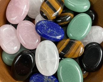 May include: A bowl filled with various smooth, oval-shaped polished stones in different colors, including pink, green, white, black, brown, and blue.