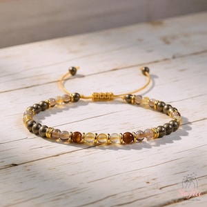 Puede incluir: Pulsera de cuentas ajustable con una mezcla de piedras preciosas doradas, marrones y transparentes. La pulsera incluye cuentas de pirita, citrino y otras piedras naturales, ensartadas en un cord&oacute;n beige con nudos corredizos ajustables.