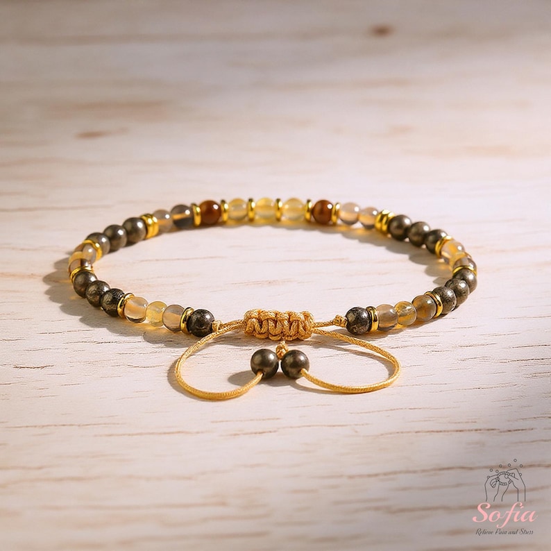 Puede incluir: Pulsera ajustable con una mezcla de cuentas doradas, marrones y grises. La pulsera incluye pirita, citrino y otras cuentas de piedras preciosas, con detalles dorados. El cierre ajustable es de cord&oacute;n beige tejido.