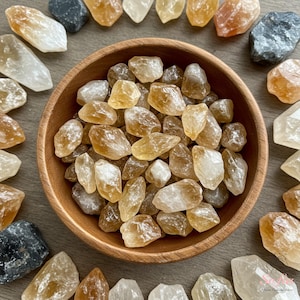 May include: A wooden bowl filled with a variety of raw, natural, yellow-orange citrine crystals. The bowl is surrounded by more citrine crystals on a wooden surface.