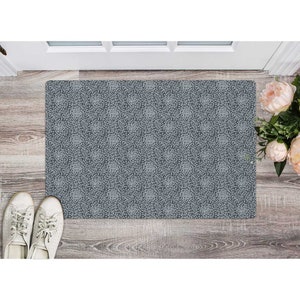 May include: A gray doormat with a white floral pattern. The doormat is made of a durable material and is perfect for high-traffic areas.