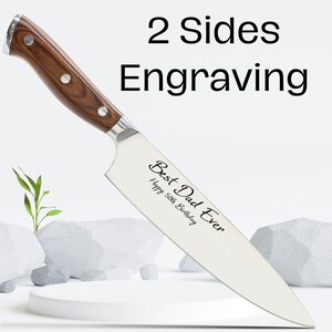 Puede incluir: Un cuchillo de chef de acero inoxidable con mango de madera. La hoja est&aacute; grabada con el texto "Best Dad Ever" y "Happy 50th Birthday".