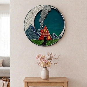 May include: A circular string art piece featuring a red house with a yellow window, a black path, blue mountains, and white smoke against a dark teal background. The design is created with white nails and colored thread on a circular frame.