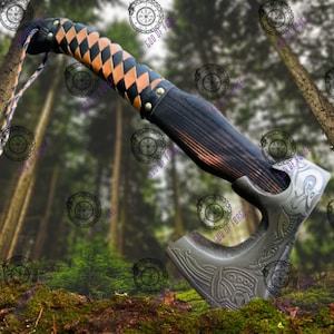 May include: A handcrafted axe with a dark wooden handle and a metal head. The handle is wrapped in a black and tan diamond pattern leather. The axe head features engraved designs. A leather strap is attached to the handle.