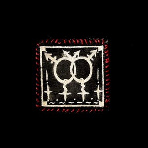 May include: Square black patch with a white interlocking gender symbol design. The patch has a red stitched border. The design includes arrows, circles, and crosses. The patch is on a black background.