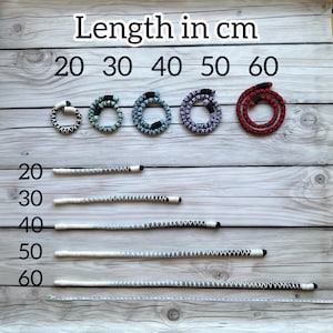 K&ouml;nnte beinhalten: Eine wei&szlig;e Holzoberfl&auml;che mit einem Lineal und f&uuml;nf Schn&uuml;ren in verschiedenen Farben und L&auml;ngen. Die Schn&uuml;re sind mit dem Text "L&auml;nge in cm" und den Zahlen 20, 30, 40, 50 und 60 beschriftet.