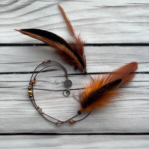 Autumn Flame – warm-toned feather hair accessory with orange and brown hues. A beautiful addition to any festival or nature-inspired look