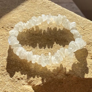 Peut inclure: Un bracelet en pierres de cristal blanches, composé de petites pierres de forme irrégulière. Le bracelet est fait avec un cordon élastique et mesure environ 18 cm de long.