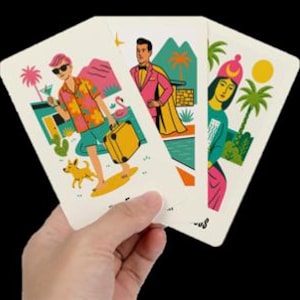 Peut inclure: Trois cartes &agrave; jouer tenues dans une main, chacune avec une illustration color&eacute;e. Une carte montre une personne avec des lunettes de soleil, un cocktail et un chien. Une autre repr&eacute;sente une personne en costume rose et cape. La troisi&egrave;me carte montre une personne avec un chapeau rose.