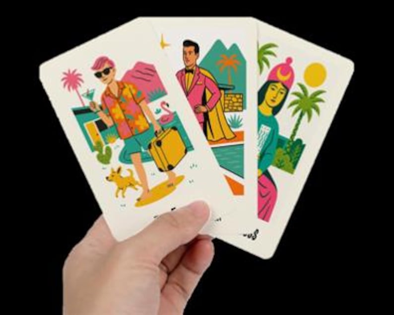 Peut inclure: Trois cartes &agrave; jouer tenues dans une main, chacune avec une illustration color&eacute;e. Une carte montre une personne avec des lunettes de soleil, un cocktail et un chien. Une autre repr&eacute;sente une personne en costume rose et cape. La troisi&egrave;me carte montre une personne avec un chapeau rose.