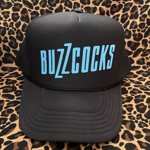 May include: Black trucker hat with a blue "BUZZCOCKS" logo.