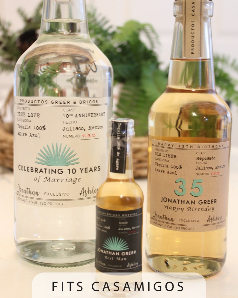 K&ouml;nnte beinhalten: Drei klare Glasflaschen Tequila mit individuellen Etiketten. Die Etiketten sind braun mit wei&szlig;em Text und einem gr&uuml;nen Agavenpflanzendesign. Die Flaschen sind mit "True Love", "Old Timer" und "Best Man" gekennzeichnet. Die Etiketten enthalten auch den Text "Tequila 100% Agave Azul" und "Celebrating 10 Years of Marriage", "Happy 35th Birthday", und "Jonathan Greer".