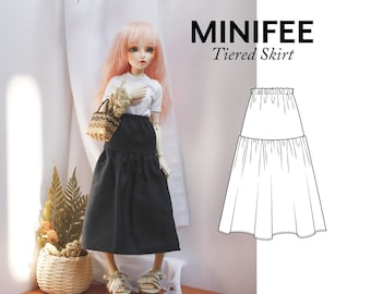 Pode incluir: Uma saia preta em camadas para uma boneca, com uma blusa branca e uma cesta de vime. A saia tem um design simples e é perfeita para uma variedade de roupas de boneca. MINIFEE Saia em camadas.