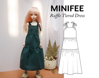 May include: A green tiered ruffle dress with black straps and bow details. The dress is shown on a doll with pink hair. The image also includes a line drawing of the dress.