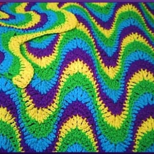 May include: A colorful crocheted blanket with a wavy pattern in shades of green, blue, yellow, and purple.