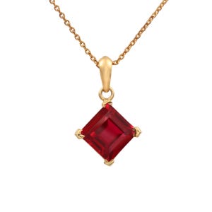 May include: A gold chain necklace with a square red gemstone pendant.
