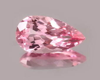 May include: A pear-shaped pink gemstone with facets, reflecting light.