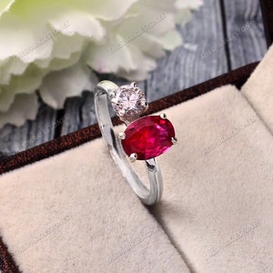 Peut inclure: Une bague en argent avec une pierre ovale rouge et une petite pierre ronde blanche. La bague est dans un écrin en velours.