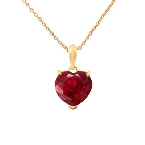 May include: A gold chain necklace with a heart-shaped pendant featuring a large, red gemstone.