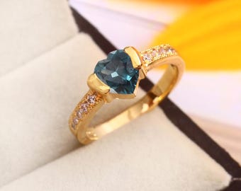 May include: A gold ring with a heart-shaped blue gemstone and a row of small clear gemstones around the band.
