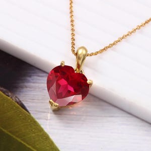 Op de afbeelding: Een gouden ketting met een hartvormige robijn hanger.