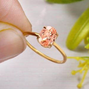 Puede incluir: Un anillo de oro con una piedra ovalada de color melocotón.