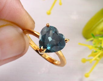 May include: A gold ring with a heart-shaped blue topaz gemstone.