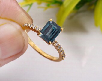 Könnte beinhalten: Ein goldener Ring mit einem blauen Edelstein und einer Reihe kleiner, klarer Edelsteine.