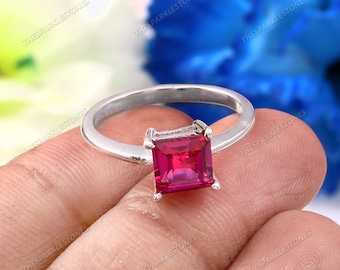Puede incluir: Un anillo de plata con una piedra preciosa rosa brillante de forma cuadrada.