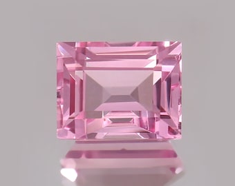 May include: A square-shaped pink gemstone with a faceted cut. The gemstone is reflecting light and has a shiny finish.