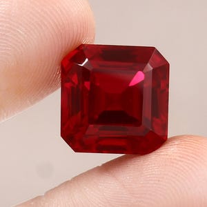 Könnte beinhalten: Ein tief roter, smaragdgeschliffener Edelstein in quadratischer Form.