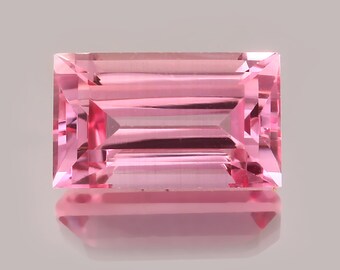 May include: A pink rectangular gemstone with a faceted cut. The gemstone is set against a grey background.