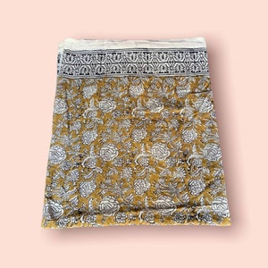 May include: A mustard yellow cotton fabric with a white floral print and a black and white border.