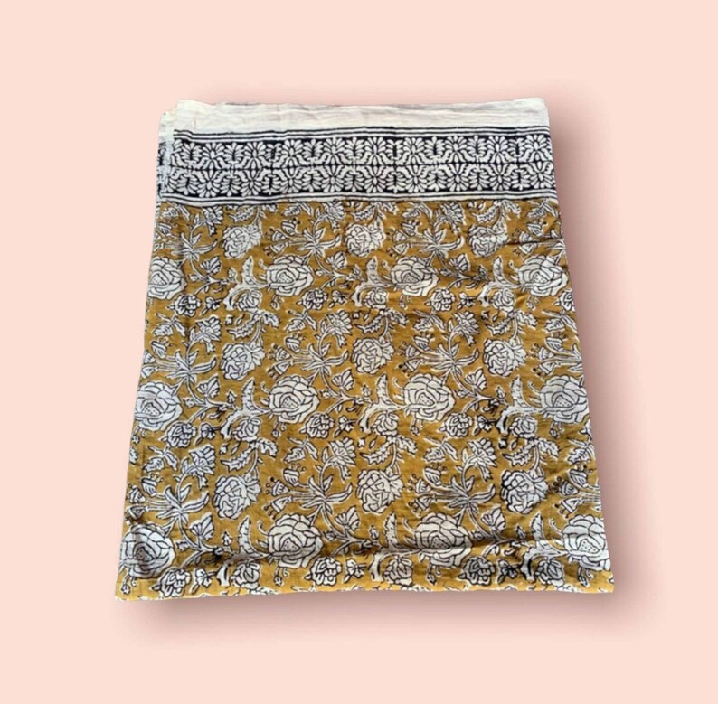 May include: A mustard yellow cotton fabric with a white floral print and a black and white border.