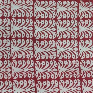 May include: A repeating pattern of white floral and leaf designs on a red background. The design is symmetrical, with each element mirroring the others. The overall effect is a decorative, textured surface.