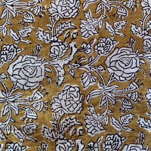 May include: A mustard yellow fabric with a white floral pattern. The flowers are stylized and have a black outline. The fabric has a vintage feel.