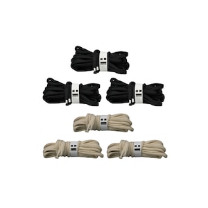 Puede incluir: Conjunto de seis carretes de cordón, tres negros y tres beige natural. El cordón está enrollado alrededor de cada carrete y etiquetado con una etiqueta blanca.