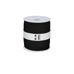 Puede incluir: Una bobina de cordón de algodón negro, envuelta en papel blanco con el nombre de la marca "Hummel" impreso en ella.