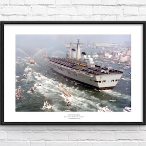 Op de afbeelding: Een zwart-witfoto van de vliegdekschip HMS Invincible die door een haven vaart. Het schip wordt omringd door kleinere boten en waterstralen spuiten water in de lucht. De foto is ondertiteld "HMS Invincible, Terugkeer uit het Falklandconflict, 17 september 1982."