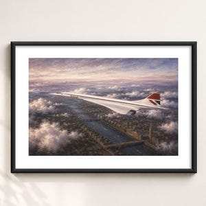 Könnte beinhalten: Ein gerahmter Druck, der ein weißes British Airways Concorde-Flugzeug im Flug über einer Stadtlandschaft mit Fluss und Wolken zeigt. Das Flugzeug hat ein rot-blaues Leitwerk. Das Kunstwerk befindet sich in einem schlichten schwarzen Rahmen.