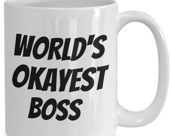 May include: White ceramic coffee mug with black text that reads "WORLD'S OKAYEST BOSS".