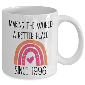 May include: White ceramic coffee mug with a rainbow design and the text "Making the world a better place since 1996".