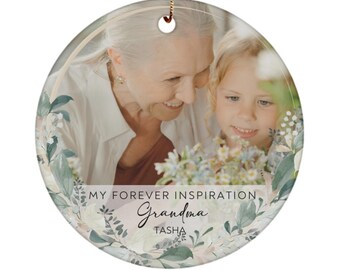 May include: A round ceramic ornament with a photo of a grandmother and granddaughter. The ornament is decorated with a floral design and the text "My Forever Inspiration Grandma TASHA".