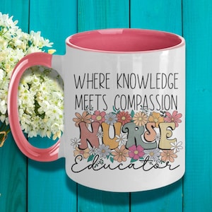 May include: White ceramic coffee mug with a pink rim. The mug features a floral design with the text "Where knowledge meets compassion Nurse Educator".