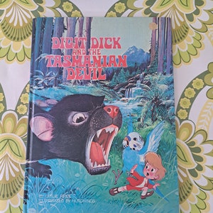 May include: A vintage children's book titled "Digit Dick and the Tasmanian Devil." The cover features a cartoon illustration of a snarling Tasmanian Devil, a child in red, and a blue bird. The background shows a forest and waterfall.