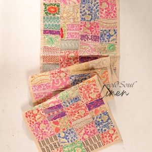 Puede incluir: Un camino de mesa de patchwork colorido con un fondo beige y una variedad de patrones florales y geométricos. El camino de mesa está hecho de retazos de tela cosidos juntos en un patrón aleatorio. El texto "Old Soul Linen" es visible en la esquina inferior derecha de la imagen.