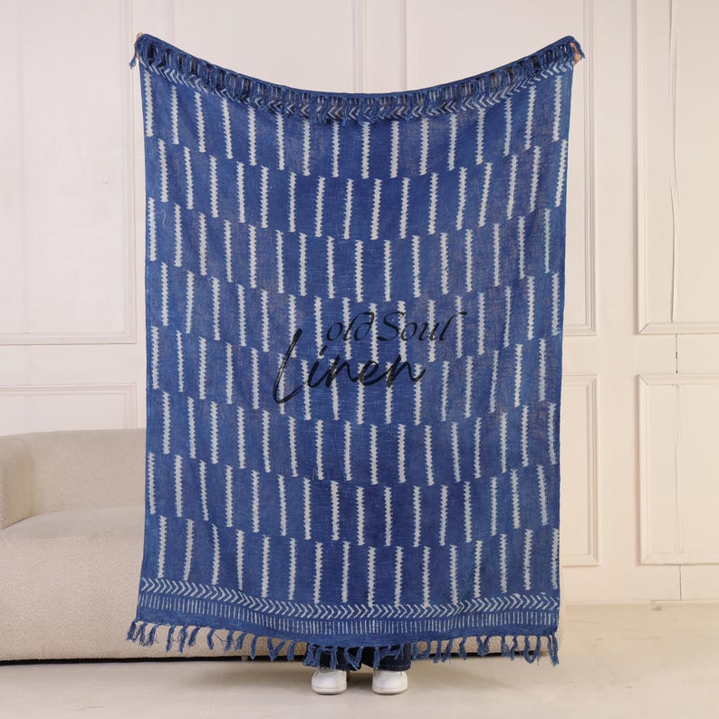 Puede incluir: Manta de lino con estampado azul y blanco con ribete de flecos. La manta presenta rayas blancas verticales sobre un fondo azul. Las palabras "Old Soul Linen" est&aacute;n bordadas en negro en la parte delantera.