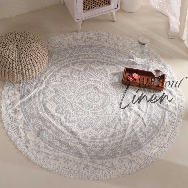 May include: A round gray and white mandala rug with a white fringe border. The rug is on a white floor and has the text "Old Soul Linen" in the lower right corner.
